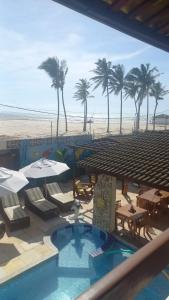 um resort com uma piscina e uma praia com palmeiras em Pousada Lua Vermelha em Caponga