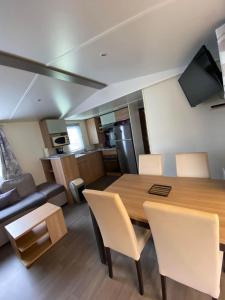 a kitchen and living room with a wooden table and chairs at camping des crocs in Saint-Quentin-en-Tourmont