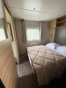 1 dormitorio con 1 cama grande y 2 ventanas en camping des crocs en Saint-Quentin-en-Tourmont