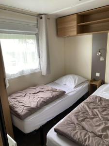 twee bedden in een kleine kamer met een raam bij camping des crocs in Saint-Quentin-en-Tourmont