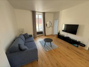 a living room with a blue couch and a flat screen tv at Bakara, élégant t2 au cœur des Halles de Biarritz in Biarritz