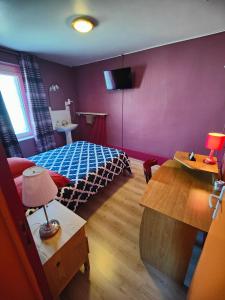 1 dormitorio con 1 cama y 1 mesa con lámpara en L'Hôtel du Mouton blanc, en Fresne-Saint-Mamès
