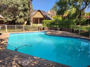 a large swimming pool with blue water in a yard at Valley Inn Guest House, Accommodation 6, Drakenstein Avenue in Sandown