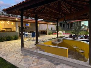 um pátio com uma parede amarela, uma mesa e cadeiras em Chácara piscinas incríveis, próximo a são paulo. em Mairinque