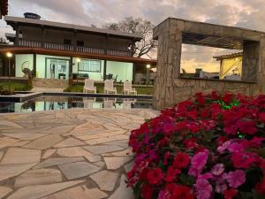 uma casa com um pátio de pedra com flores no primeiro plano em Chácara piscinas incríveis, próximo a são paulo. em Mairinque