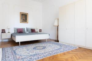a white bedroom with a bed and a rug at LittleParis in Cluj-Napoca
