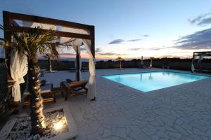 a pool with a gazebo and a palm tree at Villa Melody Novalja in Novalja
