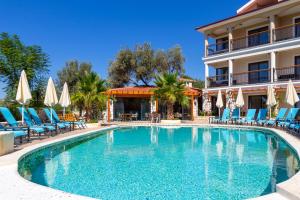 a swimming pool in front of a hotel with chairs and umbrellas at Perdikia Hill Hotel And Villas in Oludeniz