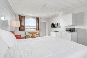 een witte slaapkamer met een groot bed en een tafel bij Cape View Motel & Cottages in Mavillette