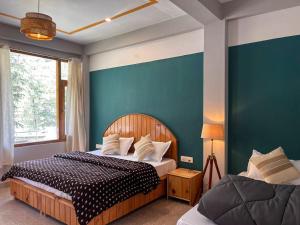 a bedroom with two beds and a blue wall at Madpackers Kasol Riverside - Katagla in Kasol