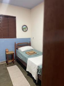 1 dormitorio con 1 cama y reloj en la pared en Sítio Vovó Chiquinha - 4km Centro Histórico en Goiás