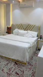 um quarto com uma cama grande com lençóis brancos e almofadas em فواصل الشمال em Rafha