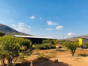 a yellow building in the middle of a field with trees at SleepOver Punda Maria Gate in Thohoyandou