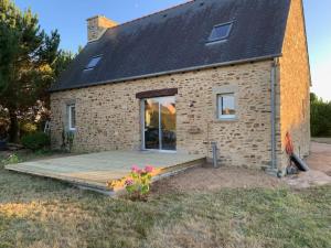 a small brick house with a wooden deck at Maison de Kermouster, juste avant le Paradis in Lézardrieux