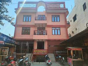 a pink building with motorcycles parked in front of it at SGH Guest House in Mathura