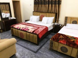 een hotelkamer met 2 bedden en een bank bij Hotel Royal inn in Lahore