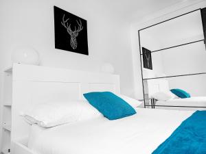 a bedroom with a white bed with blue pillows at Charming London Home, Opp Arnos Grove Underground Station, Parking in New Southgate