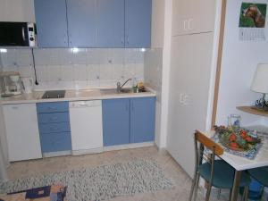 una cucina con armadi blu, tavolo e lavandino di Neues Haus mit modern eingerichteten Apartemanten und Swimmingpool a Novi Vinodolski