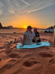 dos personas sentadas en la playa viendo la puesta de sol en Wadi Rum sky Camp en Wadi Rum