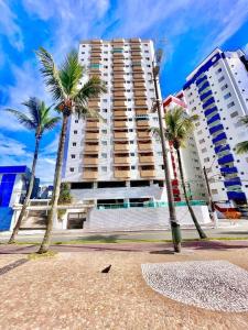 two palm trees in front of a large building at Apartamento Vista Mar Praia Grande, Ocian in Praia Grande