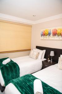 twee bedden in een hotelkamer met groen en wit bij Ushaka Waterfront Penthouse with Rooftop Jacuzzi in Durban