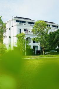 a white building with trees in front of it at Olivia Boutique Hotel in Sanxing