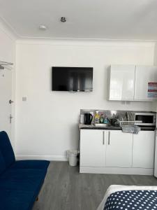 a kitchen with white cabinets and a blue couch at Starlet Property in Wanstead