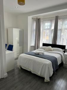 a white bedroom with a large bed and windows at Starlet Property in Wanstead