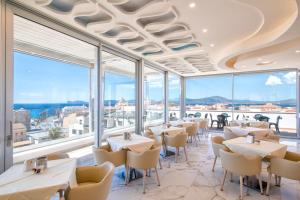 a restaurant with tables and chairs and large windows at Hotel La Margherita & SPA in Alghero