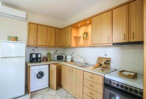 a kitchen with wooden cabinets and a washer and dryer at Olympus Beach Aigani Family House in Aigáni