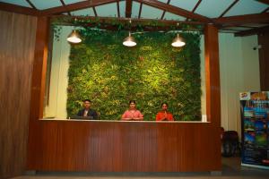 three people standing behind a large green wall at Veerdency Luxury resort in Bangalore