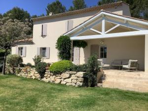 a white house with a stone wall and a patio at PERNO LI FONT villa contemporaine avec piscine in Pernes-les-Fontaines