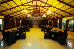 a banquet hall with black tables and chairs and chandeliers at Veerdency Luxury Resort - 3 Km to Banglore Airport in Bangalore