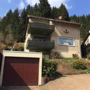 a house with a brown garage door in front of it at Freistehendes Ferienhaus in Sieber mit Terrasse, Garten und Grill in Herzberg am Harz