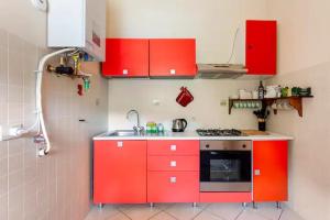 una pequeña cocina con armarios rojos y fregadero en Rifugio sul Lago di Lugano a Porto Ceresio en Porto Ceresio