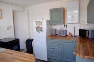uma cozinha com armários azuis e um frigorífico branco em Cosy Cottage to Relax or Explore em Mistley