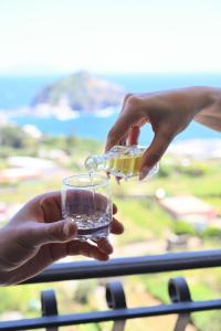 a person pouring a drink from a bottle into a glass at Villa Eleonora, un angolo di Paradiso ad Ischia in Ischia