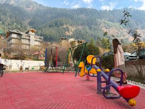 a young girl standing next to a playground at Hill Rive Resort Near Mall Road in Manāli