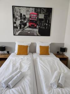 Duas camas com lençóis brancos e um autocarro de 2 pisos vermelho. em Evita Studio Apartment em Karlovac