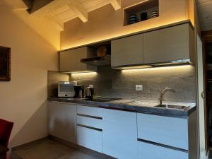 a kitchen with white cabinets and a sink at Maison Tatà in Aosta