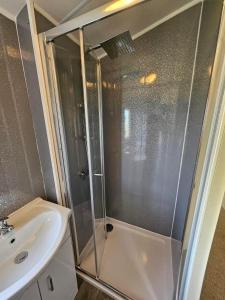 a shower with a glass door next to a sink at 6 berth Seawick Caravan Park, St Osyth in Colchester