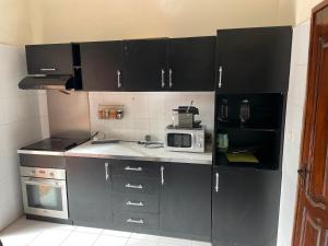 cocina con armarios negros y microondas en Villa à Thiès avec piscine à 15mn de l'aéroport, en Thiès