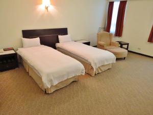 een hotelkamer met 2 bedden en een stoel bij Herkang Hotel in Taichung