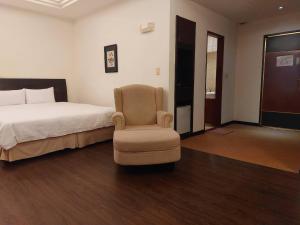 a bedroom with a bed and a chair at Herkang Hotel in Taichung