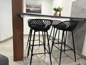 two black bar stools sitting at a counter in a room at Le Colibri-Park. gratuit- Prox.Musée automobile in Mulhouse