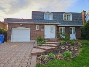 a brick house with white doors and a driveway at Gorgeous 5 Bedroom House in Brossard