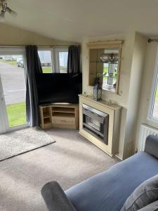 1 dormitorio con 1 cama y TV de pantalla plana en 6 berth Seawick Caravan Park, St Osyth en Colchester