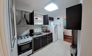 - une cuisine avec des armoires noires et un réfrigérateur blanc dans l'établissement Cómodo apartamento frente Quinta Presidencial, à Florida