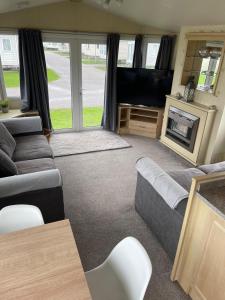 sala de estar con sofá y TV de pantalla plana en 6 berth Seawick Caravan Park, St Osyth en Colchester