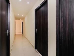 a corridor with a black door and a hallway with white walls at OYO Pradhann Home Stay in Kalimpong